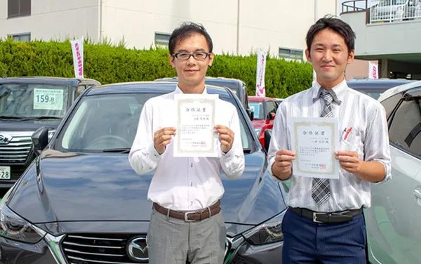 資格の証明書をもった大嶋カーサービス社員の写真